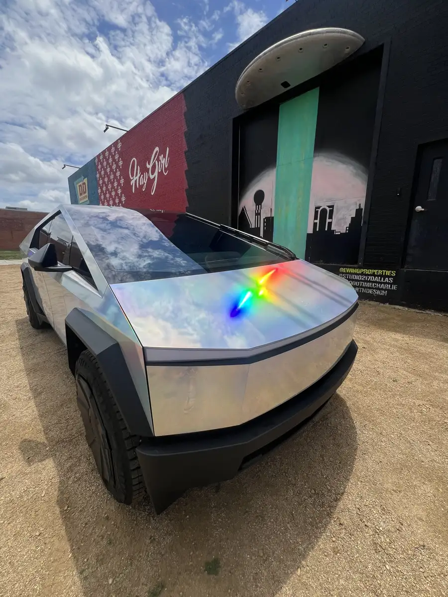 Holographic Cybertruck front three-quarter view by a painted mural