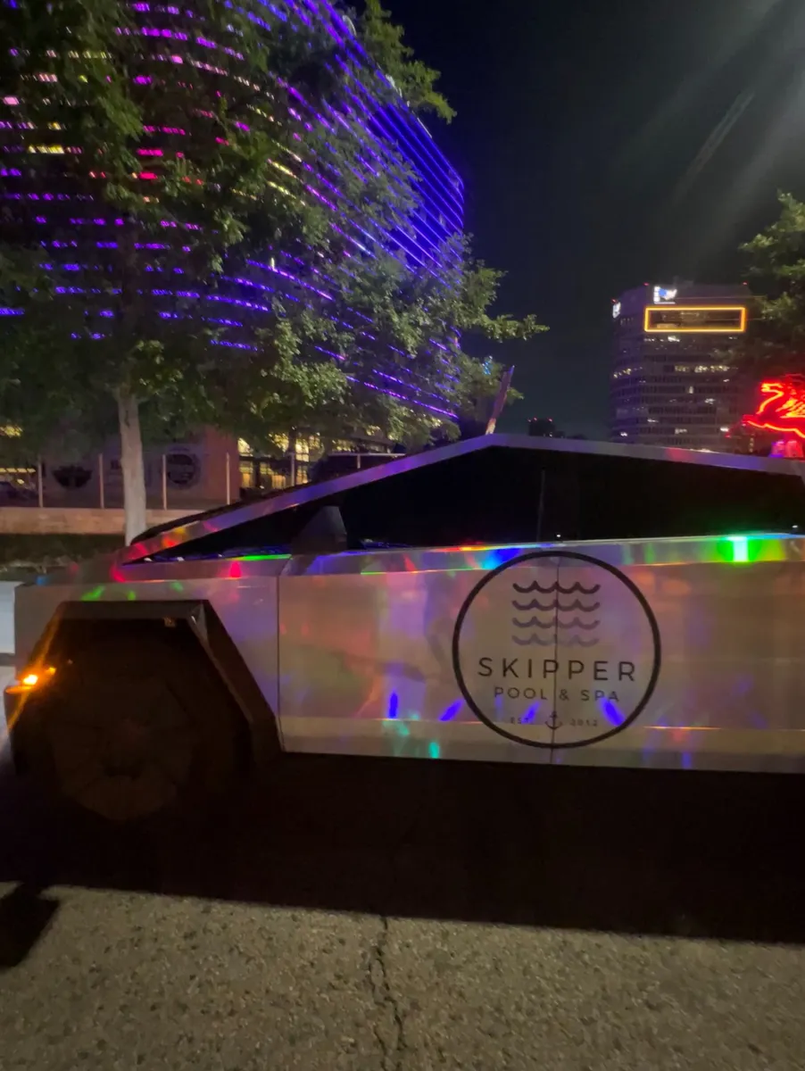 Skipper Cybertruck door logo at night under purple building lights
