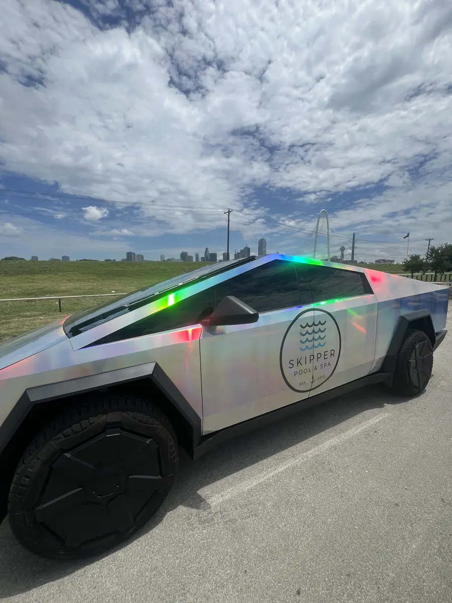 Skipper Cybertruck in a field with the Dallas skyline
