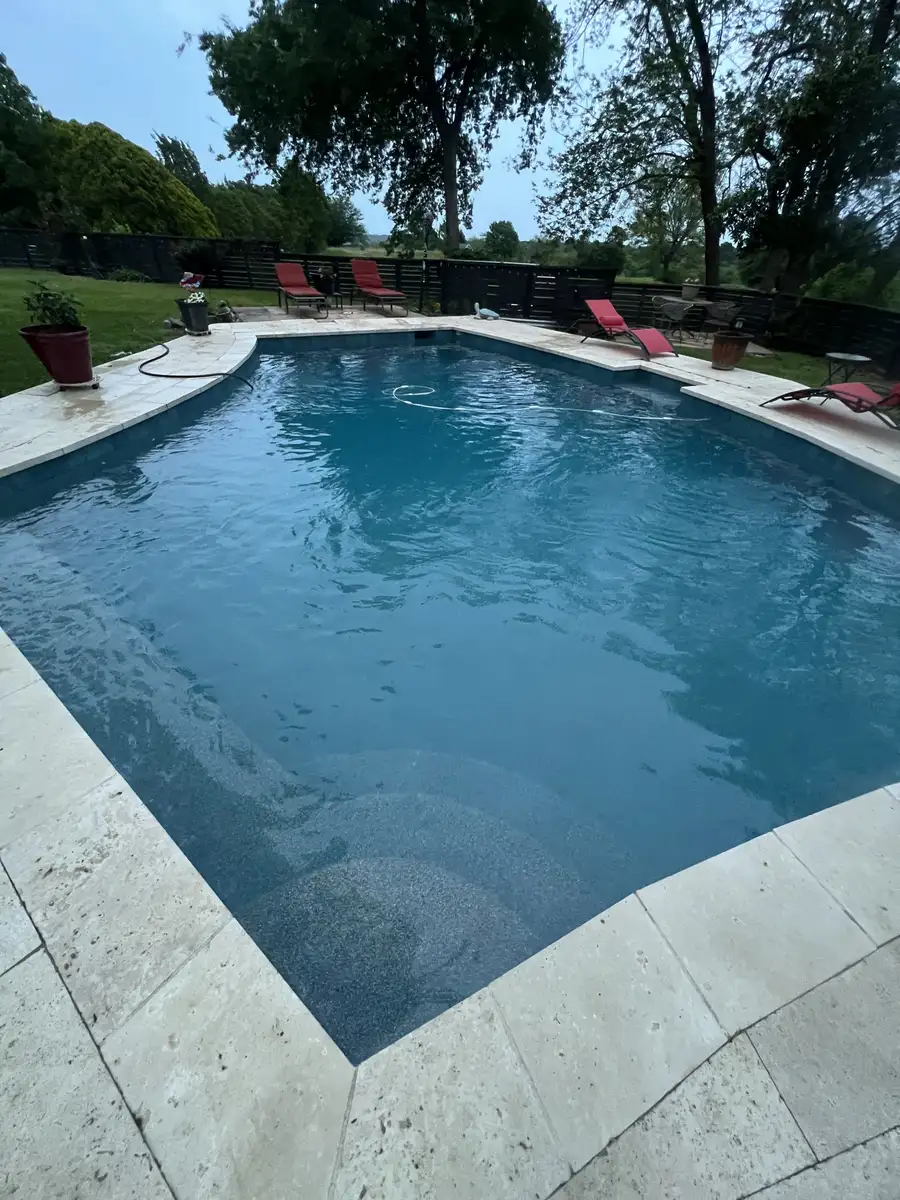 Clear rectangular pool with red lounge chairs