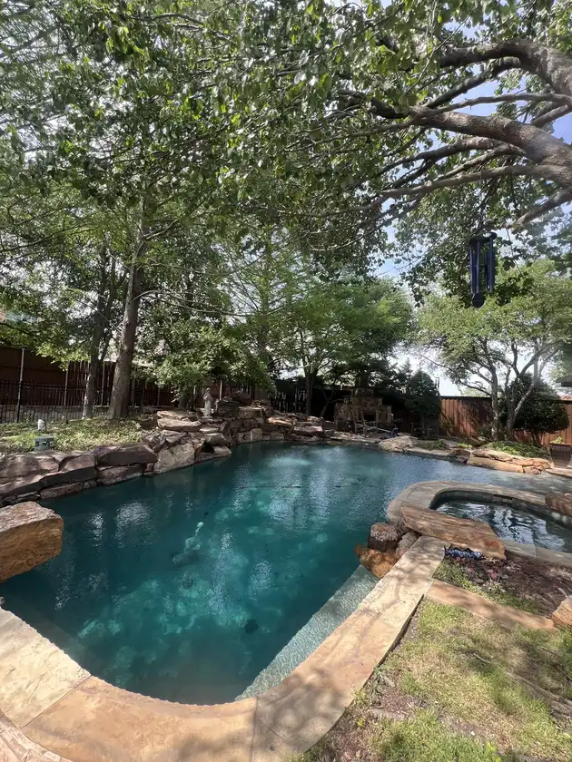 Rock-edged pool and spa under shade trees