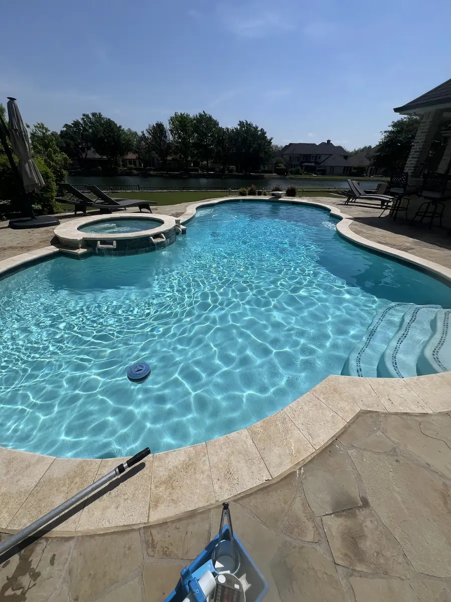 Clear pool and spa with a tree line behind