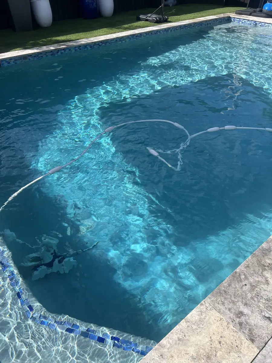 Clear pool with blue tile and a cleaner