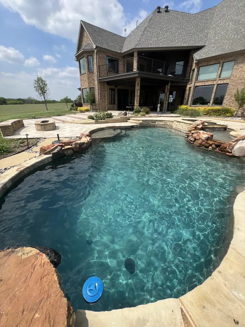 Freeform pool with rock waterfall by the house