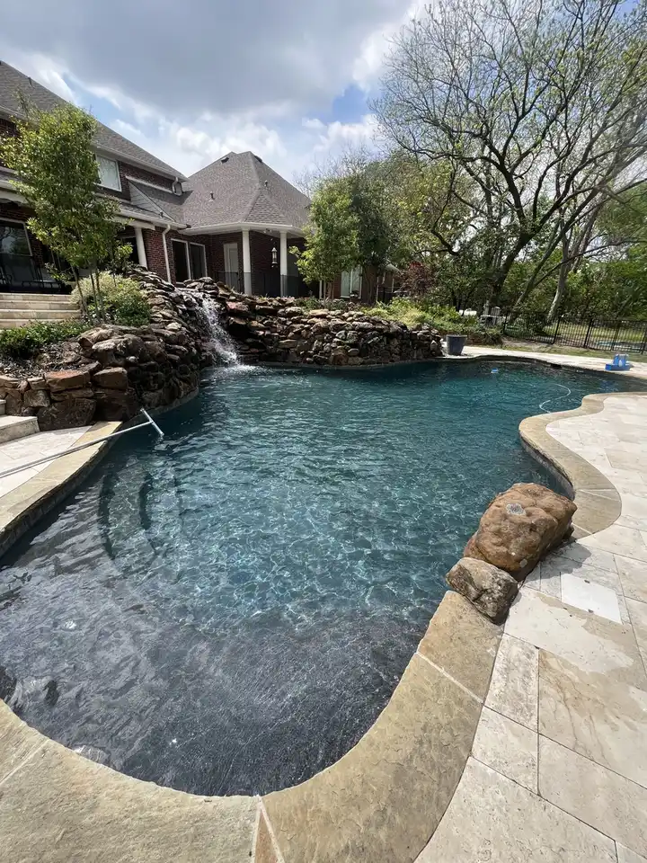 Pool with rock waterfall by the house