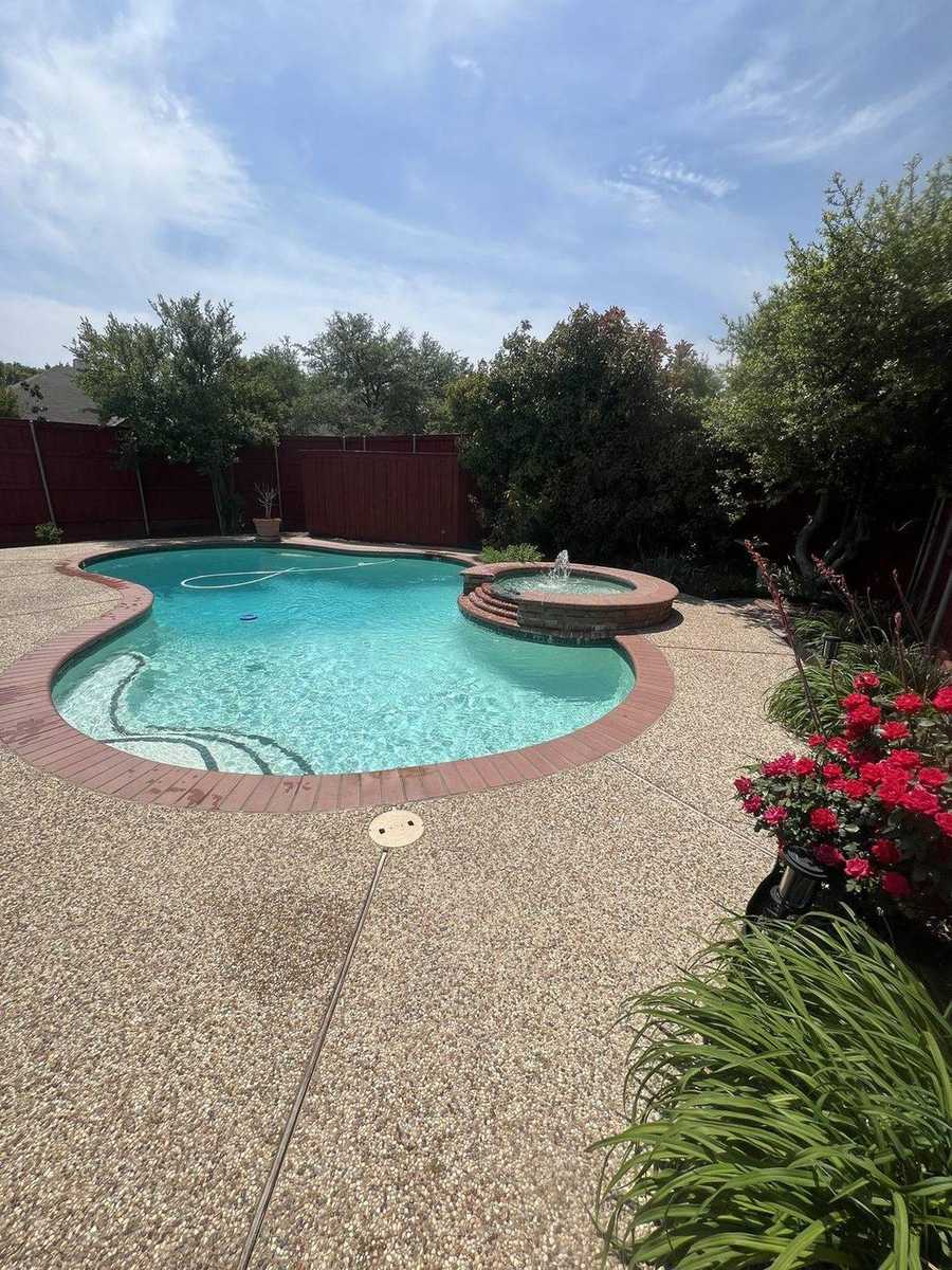 Freeform pool with brick spa fountain and rose garden