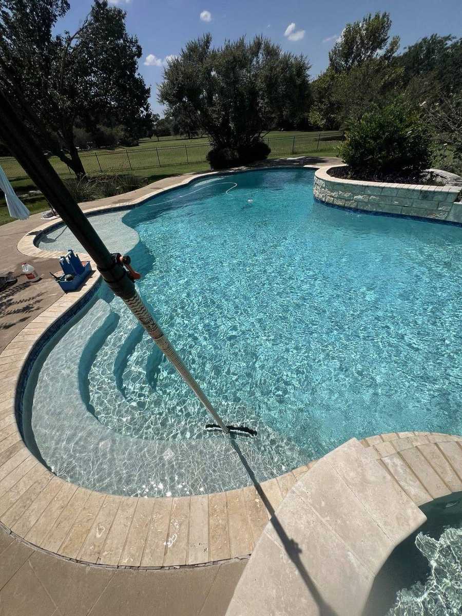 Weekly service — brushing a clear pool with the pole