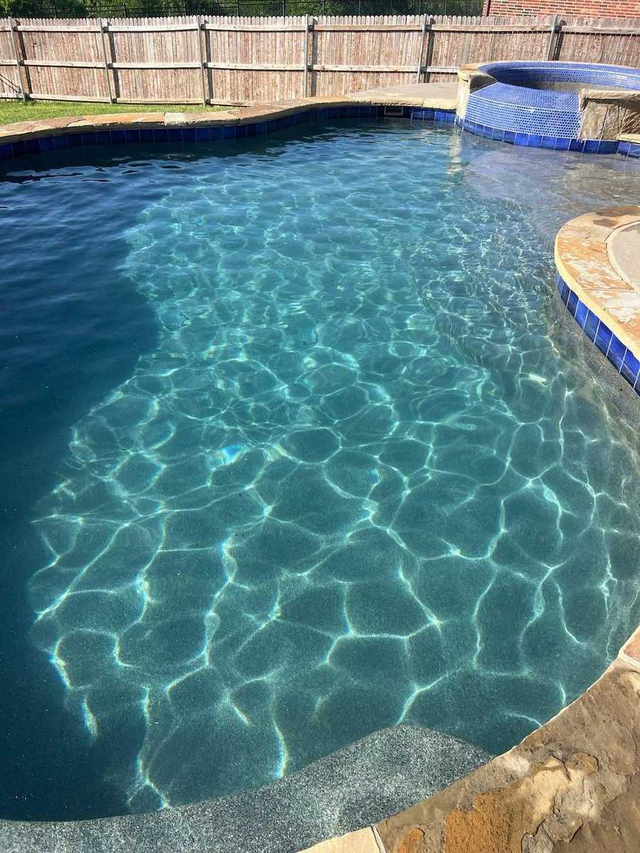 Dark plaster pool with blue mosaic spa and flagstone deck