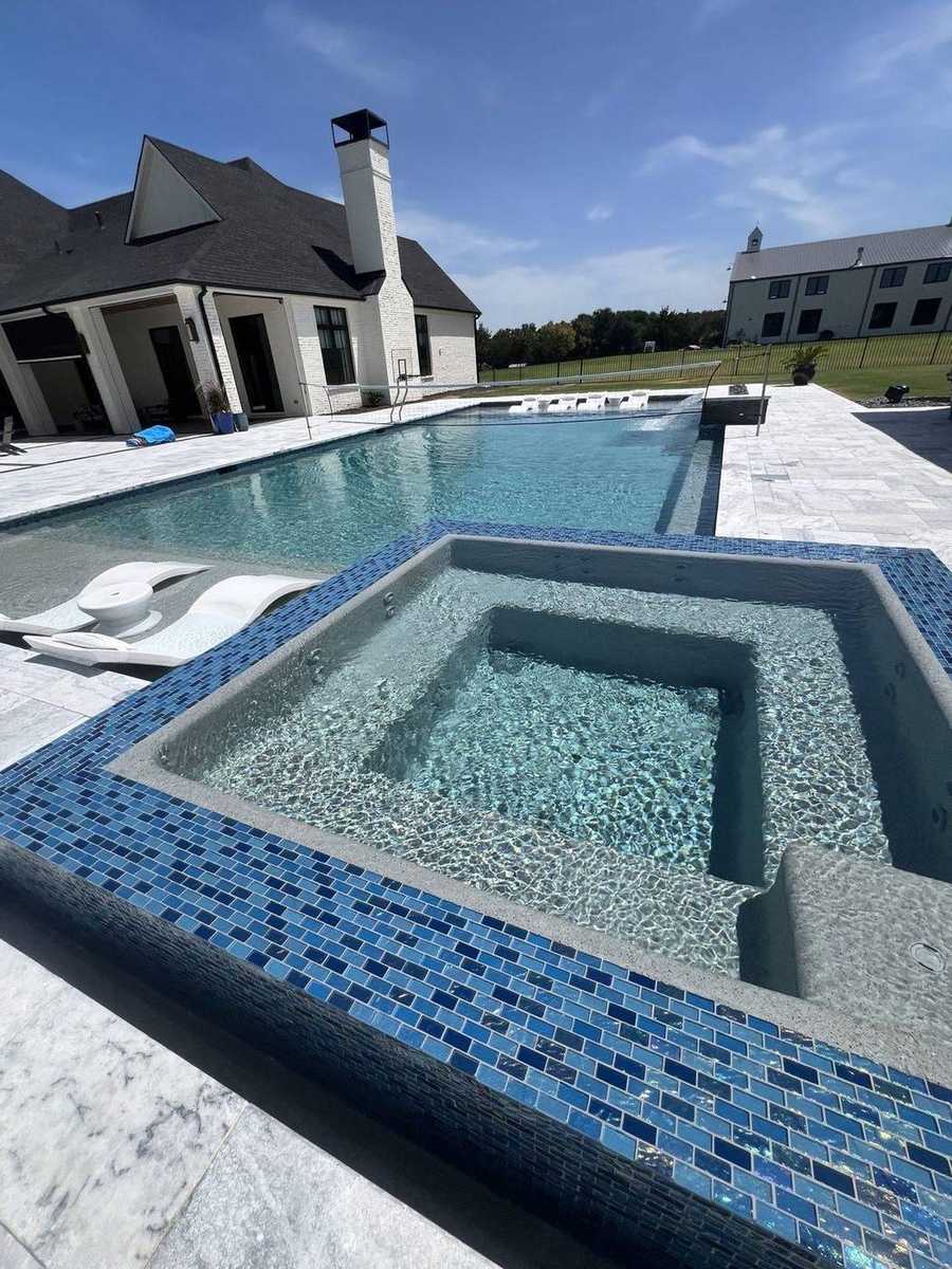 Modern spillover spa with blue mosaic tile and rectangular pool