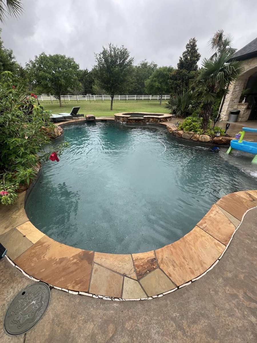 Freeform dark pool with raised spa and flagstone deck
