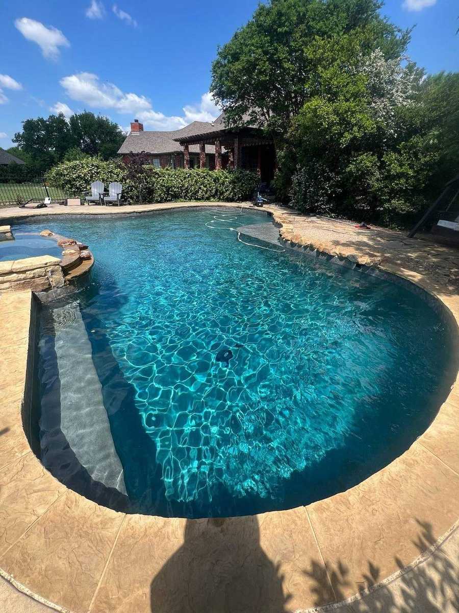 Freeform dark plaster pool with raised spa spillway