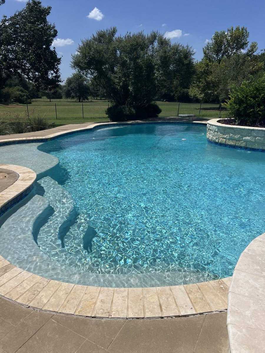 Clear residential pool with sun shelf and stone coping
