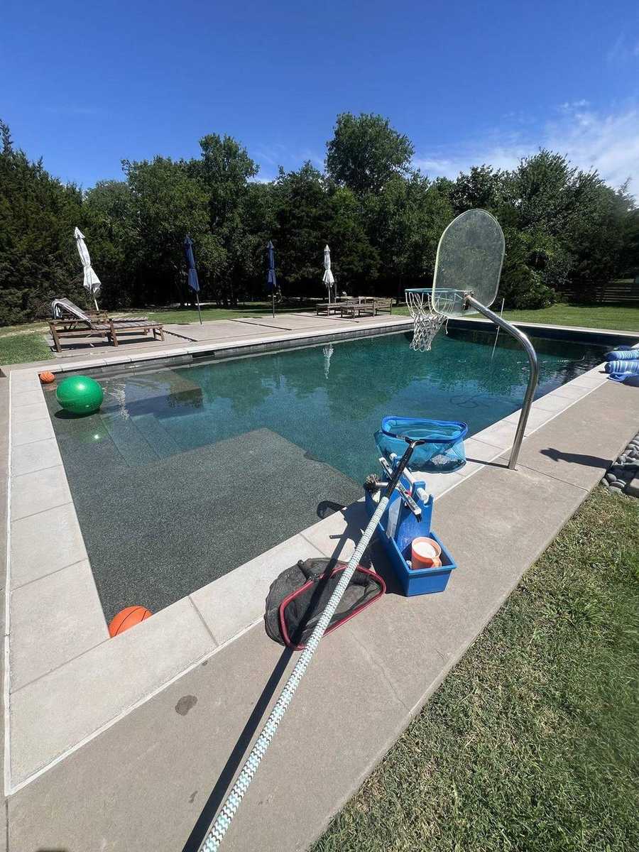 Deep teal pool with tanning ledge and service gear on the deck