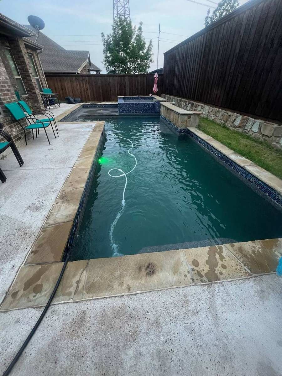 Dark teal pool with mosaic spa and privacy fence
