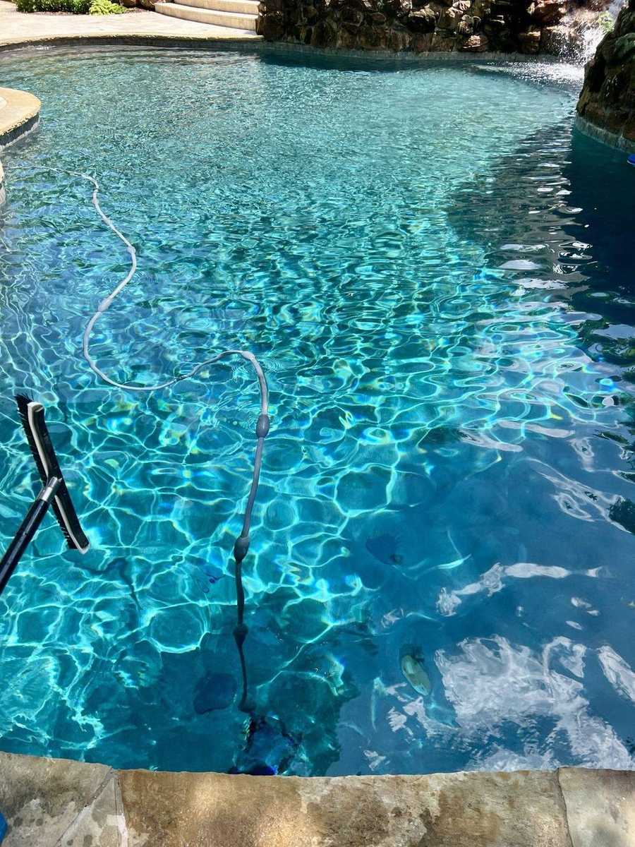 Pool with rock waterfall feature and automatic cleaner
