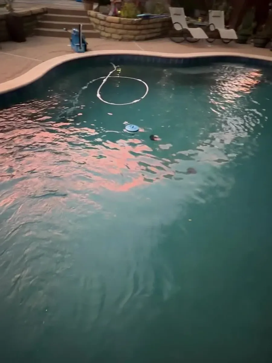 Pool lights casting pink reflections on the water at night