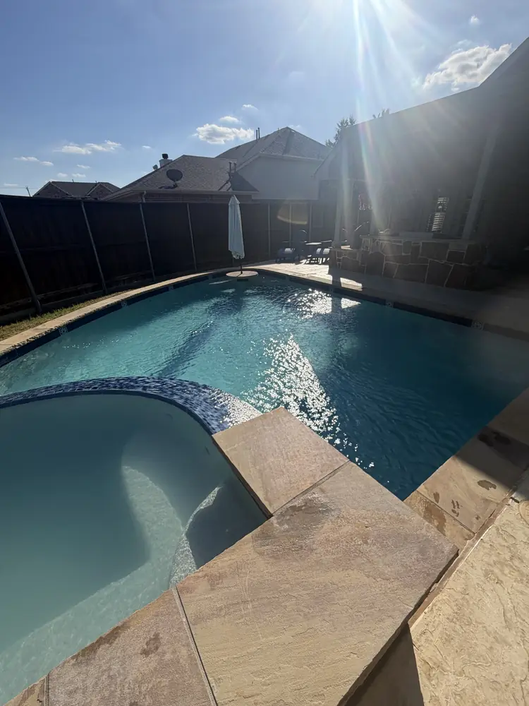 Clear pool and spa with sun flare over the backyard