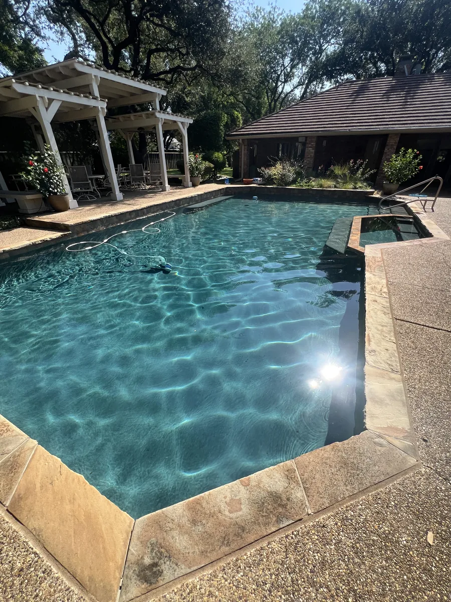 Clear pool beside a pergola with sun flare on the water
